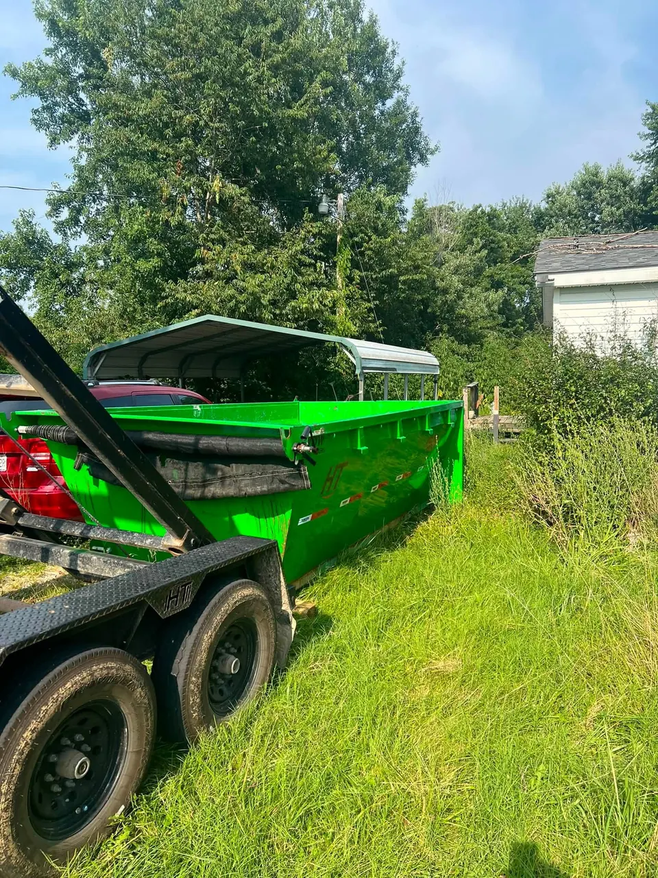 Roll-off dumpster placed on a grassy rural lot for a cleanup job